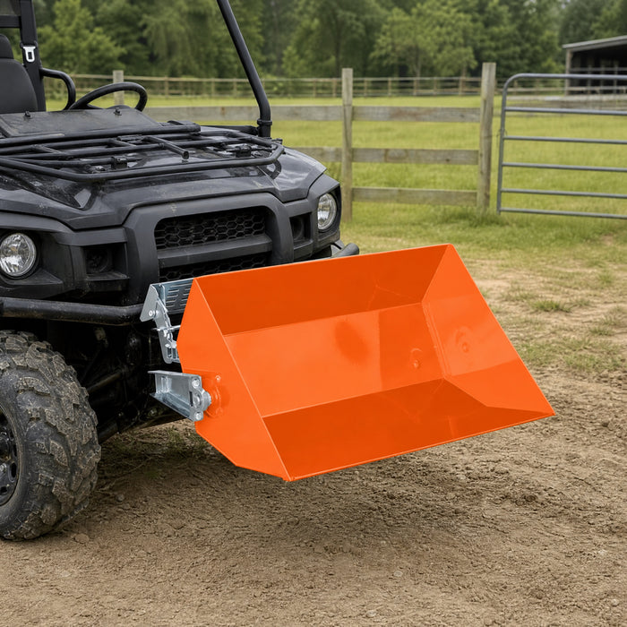 TMG-ATD35 orange dumping bucket mounted on the front of a UTV beside a pasture fence.