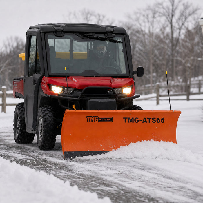 TMG-ATS66 snow blade mounted on a UTV pushing snow along a driveway in winter.