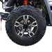 Close-up of black alloy wheel and knobby tire on ATV.