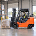 Operator driving 3 Ton LPG Forklift carrying pallet inside warehouse