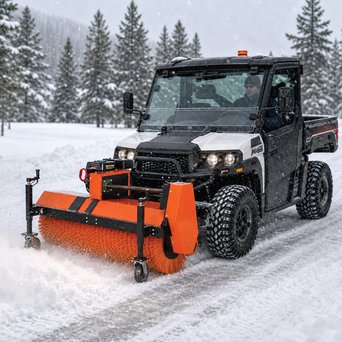 TMG-GSS47 rotary snow sweeper mounted on a UTV clearing a snow-covered road beside evergreen trees.