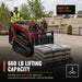 Operator using 36" pallet fork on compact loader lifting pallet outdoors.